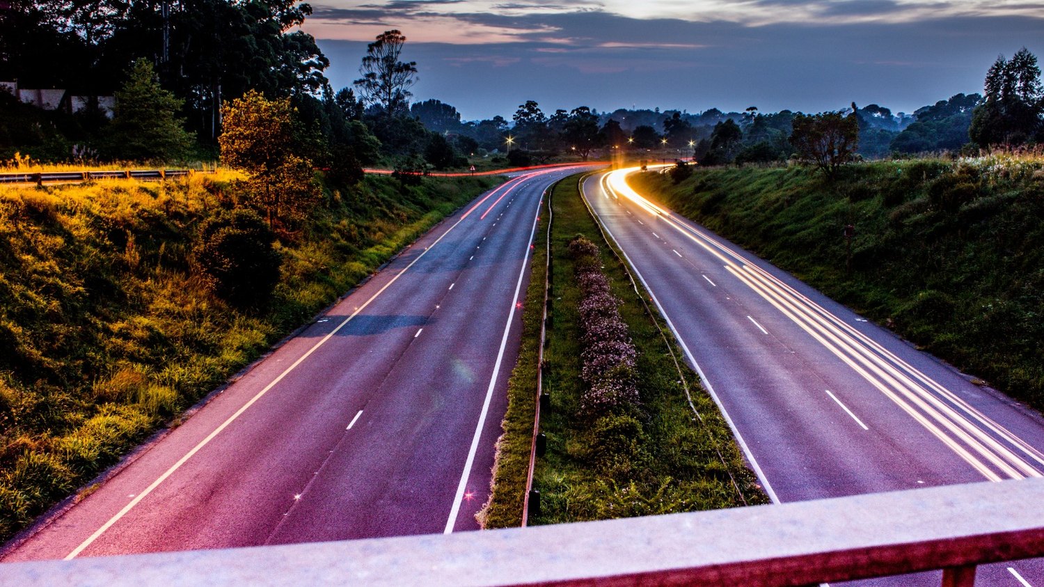 Dusk highway seen from an overpass, with vehicle light trails